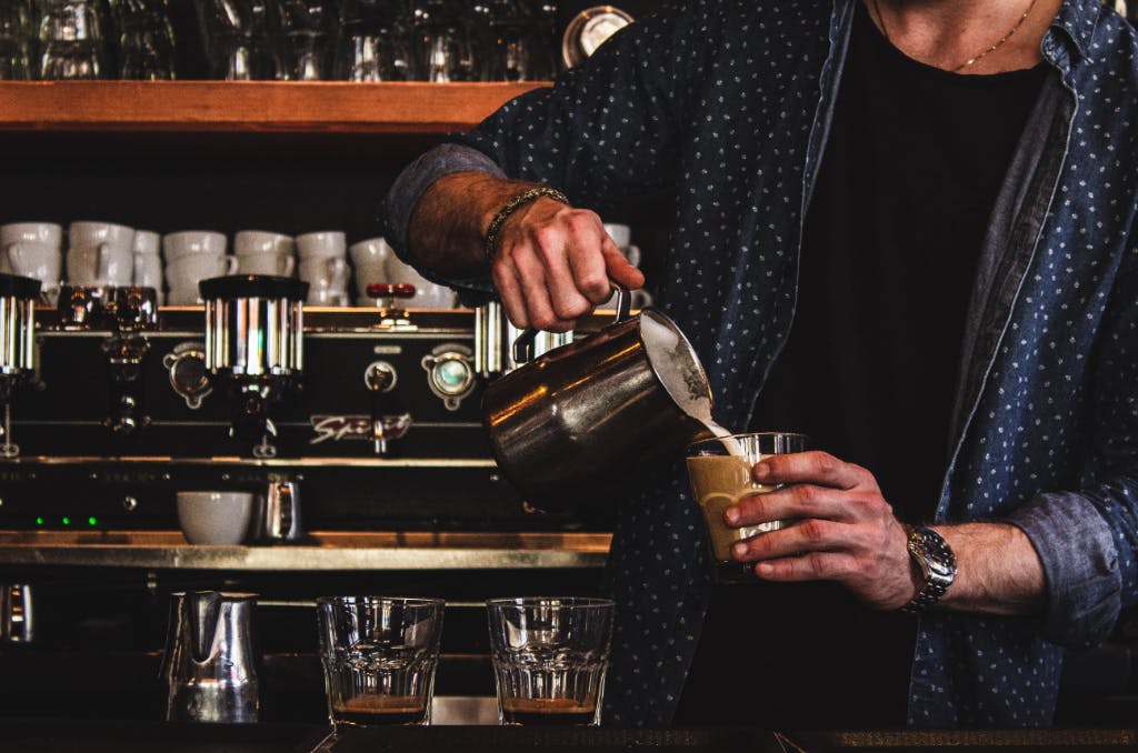 male pouring a latte in a bar